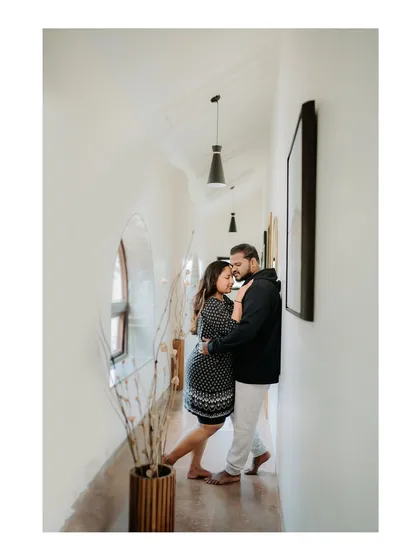 An intimate embrace in a hallway, captured with a focus on their connection and the clean lines of the interior.
