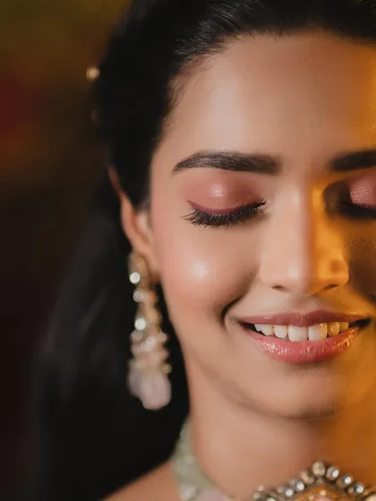 A close-up on this bride's happy, glowing face. For her Haldi look, I focused on creating a fresh, luminous base that would last all day, with a pop of color on the eyes for a playful touch.