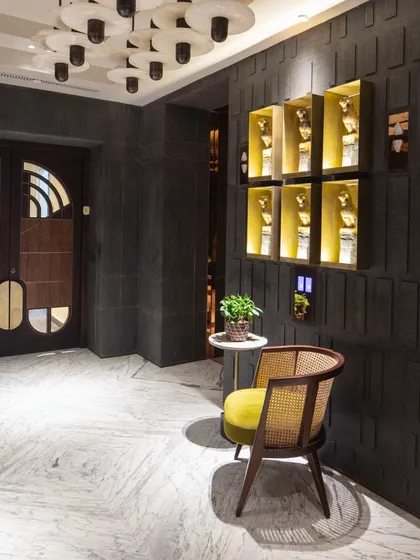 The entrance to 'The 42' in Kolkata, featuring honed granite walls and a crafted main door. The foyer showcases a Revati Sharma Singh installation, setting a tone of artistic luxury from the moment of entry.