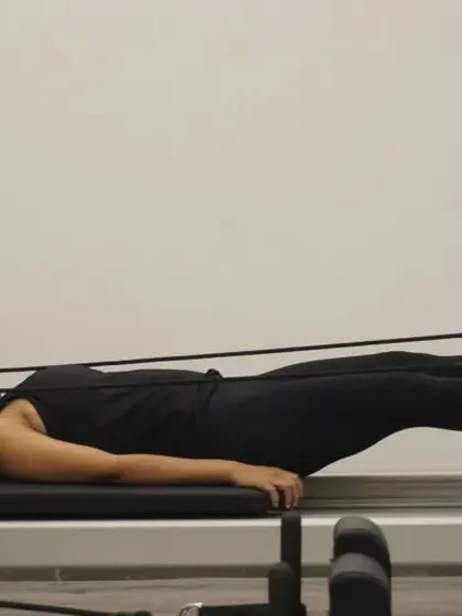 A client works on leg circles with feet in straps on the reformer. This is a great exercise for hip mobility and core control.