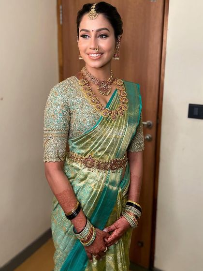 The complete look is a picture of elegance. The makeup perfectly complements her sea-green silk saree and traditional gold jewelry.