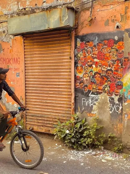 A cyclist pauses to look at the collage of faces on the Chapel Road wall. These images document how the public interacts with and becomes part of the street art scene.