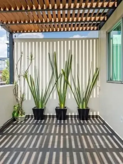 A compact balcony transformed with a wooden rafters pergola and a vertical privacy screen. This setup creates a cozy, shaded nook, demonstrating how even small spaces can become functional outdoor retreats.