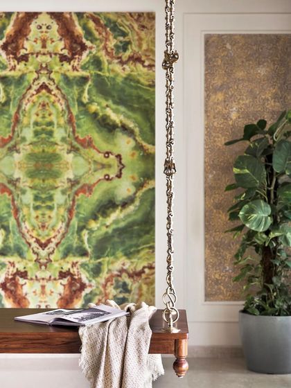A close-up of the traditional wooden swing against the dramatic green marble-patterned tile, showing the intricate brass chain details.