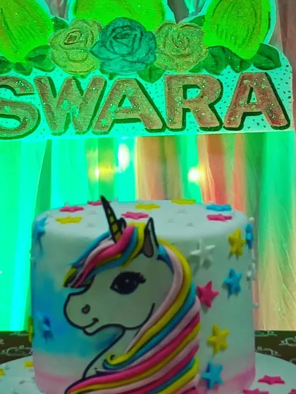 A beautiful unicorn-themed cake for Swara's birthday, featuring a rainbow-maned unicorn and colorful stars.