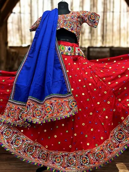 A classic red chaniya choli with intricate multi-color embroidery and mirror work along the border. The contrasting royal blue dupatta makes the entire outfit pop.