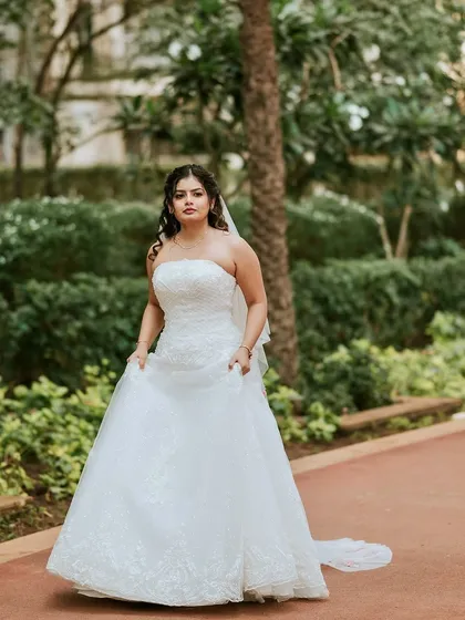 A full-length shot of the bride, looking confident and beautiful. The simple, elegant gown is perfectly complemented by her soft, natural makeup.