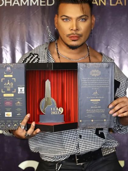 A celebrity attendee showcases the intricate details of the International Iconic Awards invitation. The multi-panel design includes event information, sponsor logos, and a central display piece, making it a true collector's item.