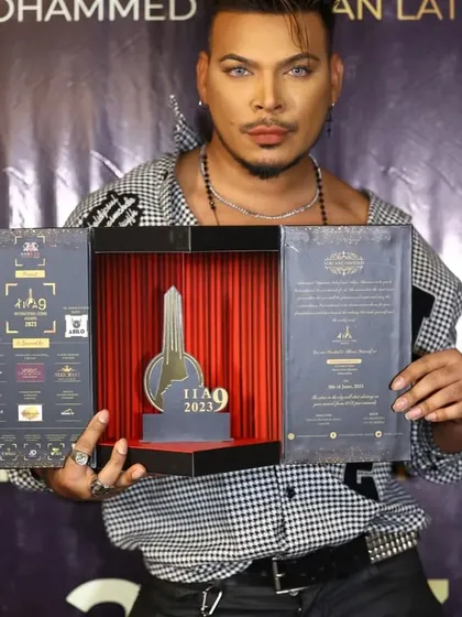 A celebrity attendee showcases the intricate details of the International Iconic Awards invitation. The multi-panel design includes event information, sponsor logos, and a central display piece, making it a true collector's item.