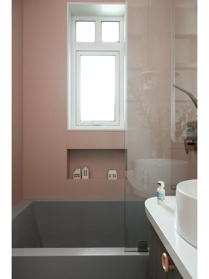 A custom-made grey bathtub is set against soft pink fluted tiles in this daughter's bathroom. The design is a perfect blend of her favorite color with a sophisticated, modern aesthetic.