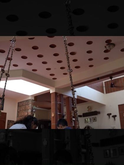 The interior of the Manjunath Residence, featuring a ceiling with inset terracotta pots (part of a filler slab system) and a central swing, blending traditional aesthetics with sustainable building techniques.