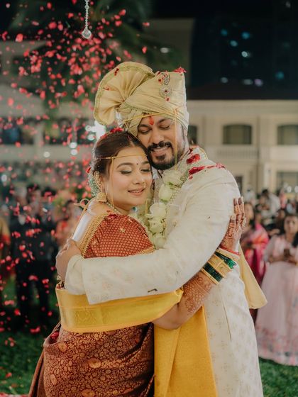 A heartfelt embrace at the end of the ceremony, with guests celebrating in the background. This photo is filled with the emotion and energy of the moment.