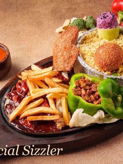 Our Chef Special Sizzler is a complete meal. It includes flavourful rice, a vegetable cutlet, fries, and a stuffed capsicum, all served on a sizzling hot plate with our special sauce.