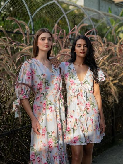 An outdoor campaign shoot for Tangerine Tiger, with two models in complementary floral dresses set against a natural, rustic background.