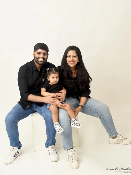 A simple and sweet family portrait. The parents and their daughter are dressed in casual black shirts and jeans, creating a relaxed and relatable family photo.