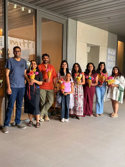 A smiling group of participants, including adults and a child, pose together holding the beautiful origami flower bouquets they created during our workshop. These sessions are great for all ages and leave everyone with a handmade treasure.