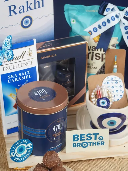 To protect the bond that protects you, I designed this 'Shielded in Blue' Rakhi hamper. It features an evil eye theme for good luck, combining premium chocolates, gourmet popcorn, and a men's grooming kit, all in sophisticated shades of navy blue.
