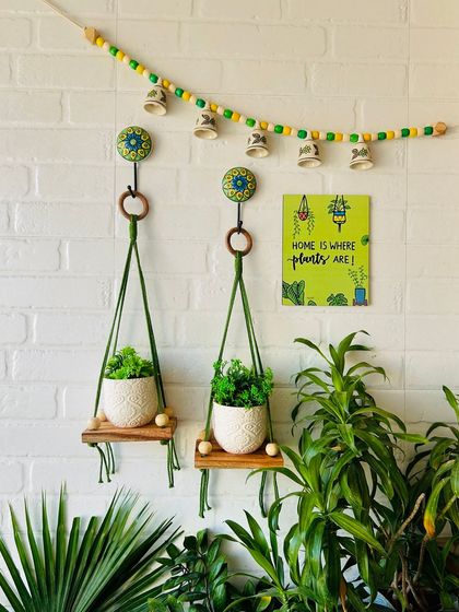 This beautiful arrangement features two natural wood rope wall shelves with ceramic planters, a bell bunting, and a wooden frame. It's a complete set that brings together the beauty of handcrafted decor to elevate your space.