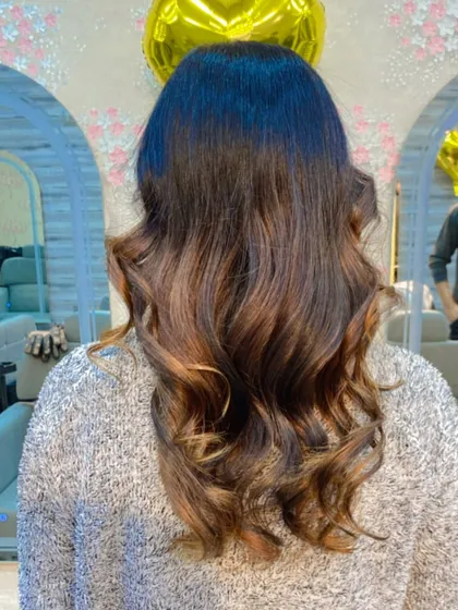A soft balayage with natural brown and caramel tones, styled with gentle waves for a sophisticated look.