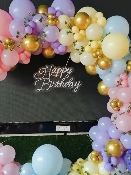 A close-up of the pastel rainbow balloon arch, showing the mix of colors and gold accents.