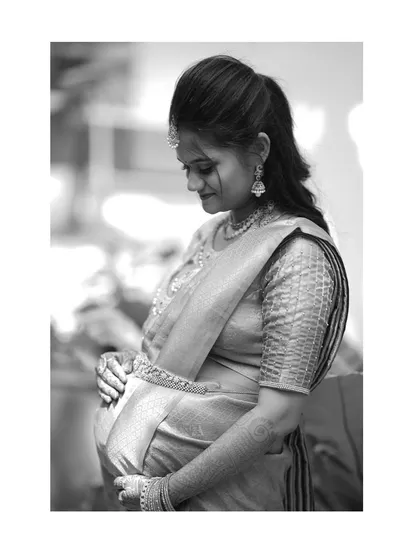 A black and white portrait of a pregnant woman, tenderly holding her belly. The simplicity of monochrome adds a timeless and emotional quality to the image.