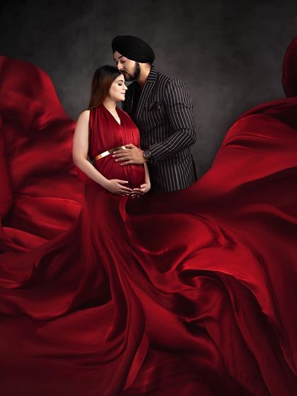 A dramatic and passionate couple portrait. The rich red of the flowing gown envelops the couple, creating a powerful and visually stunning image of their connection.