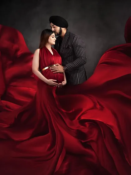 A dramatic and passionate couple portrait. The rich red of the flowing gown envelops the couple, creating a powerful and visually stunning image of their connection.