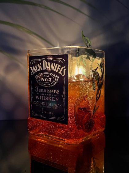 Another angle of the lit Jack Daniels candle, highlighting the sparkling gel wax and the rustic botanicals inside.