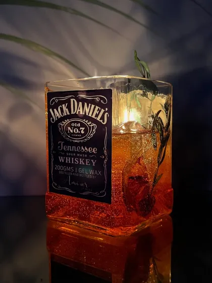 Another angle of the lit Jack Daniels candle, highlighting the sparkling gel wax and the rustic botanicals inside.