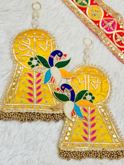 This bright yellow latkan set with colorful peacock embroidery is sure to brighten any space. The golden bead tassels complete the festive look.