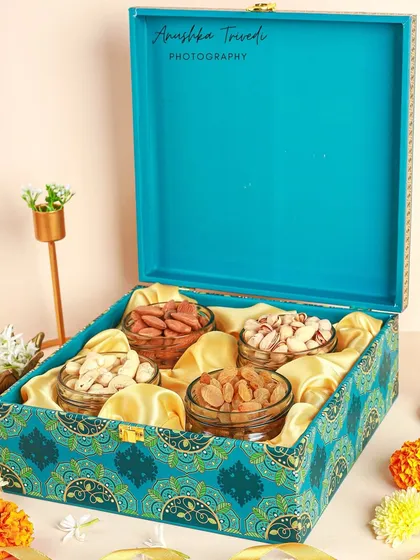 Another angle of the beautiful turquoise dry fruit box, this time closed to showcase the lid's design. The styling with flowers and a traditional lamp completes the festive look.