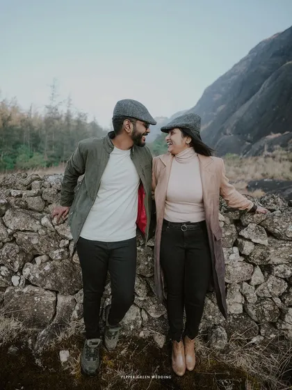 A portrait of the couple looking at each other, their matching caps and classic coats adding to the vintage charm of their pre-wedding shoot.
