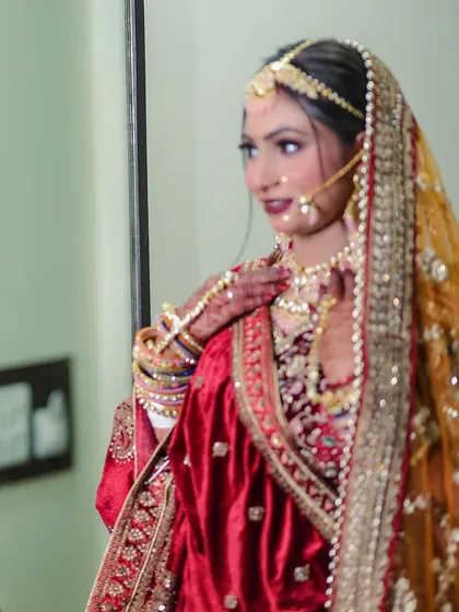 A classic bridal portrait showing the bride looking in the mirror. This shot captures a moment of quiet reflection and admiration as she sees her complete bridal look for the first time.