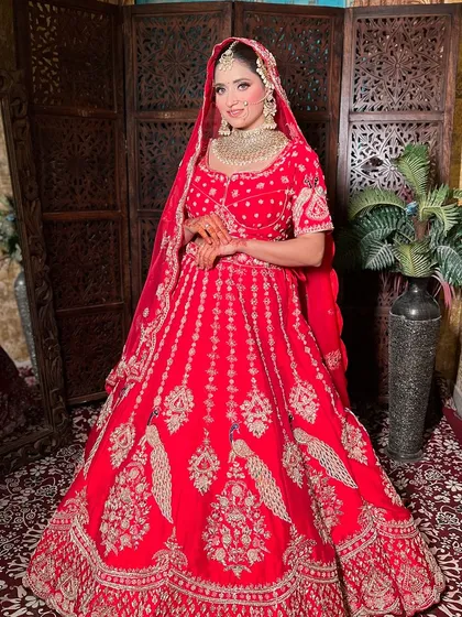 A happy bride posing in her red wedding lehenga. The perfect fit and intricate design details are clear to see.