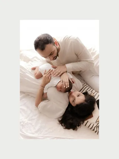 The color version of a tender family moment. The soft, natural light from the side highlights the peaceful expressions of the parents as they watch over their sleeping newborn, creating a warm and serene atmosphere.