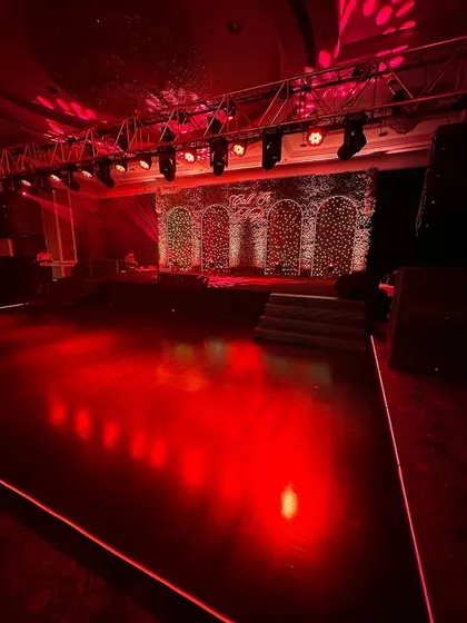 The sangeet stage lit with dramatic red spotlights, ready for a night of performances.