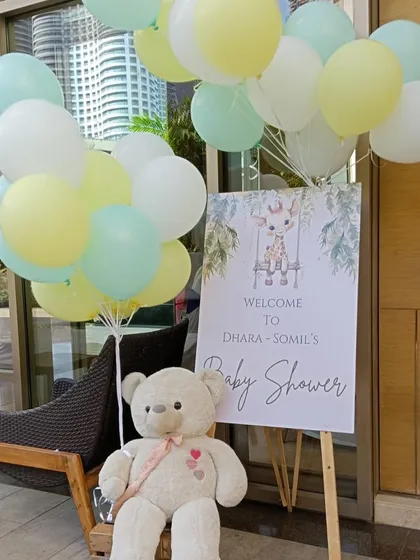 The welcome sign for the safari-themed baby shower, featuring a cute giraffe illustration and a teddy bear holding pastel balloons.