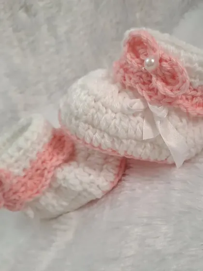 A classic design, these white booties feature a soft pink cuff and a matching pink bow with a single pearl in the center.