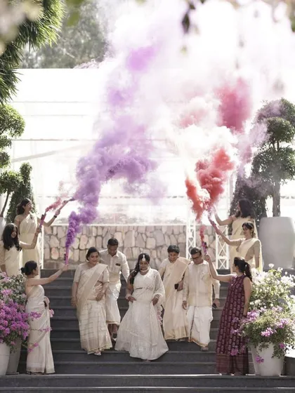 A dramatic bridal entry for a Nischitartham, with bridesmaids holding colorful smoke flares. This creates a vibrant and celebratory start to the event.