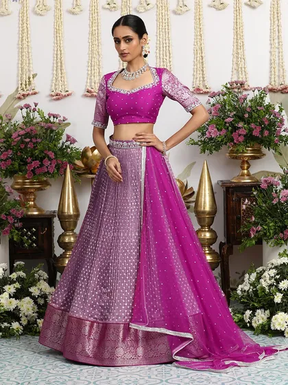 A stunning ombre-effect lehenga in shades of magenta and lilac, created with Bandhani craft and paired with an embroidered blouse.