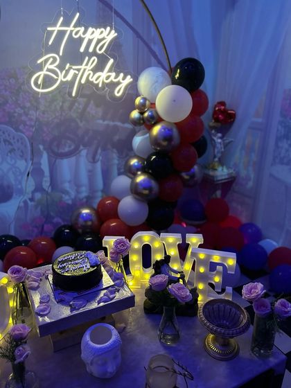 A close-up of the table decor in the smoky lounge, with a neon sign, 'LOVE' marquee letters, and fresh roses.