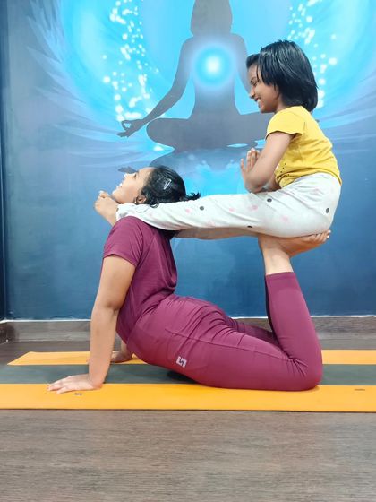 A playful and heartwarming moment between an adult and a child in a partner backbend. Yoga is for all ages.
