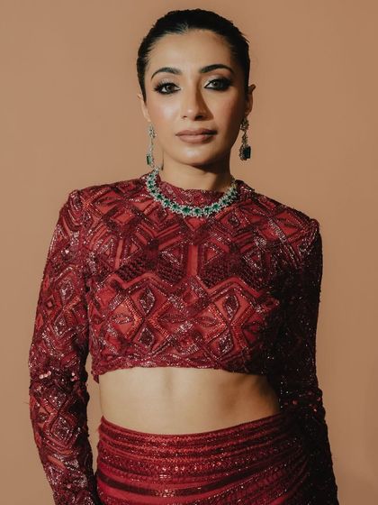 A portrait of the bride showcasing her sleek hair and makeup, which provides the perfect balance to her bold, embellished red top.