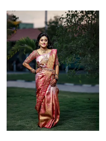 An elegant full-length bridal portrait, showcasing the bride's stunning pink saree and confident pose.