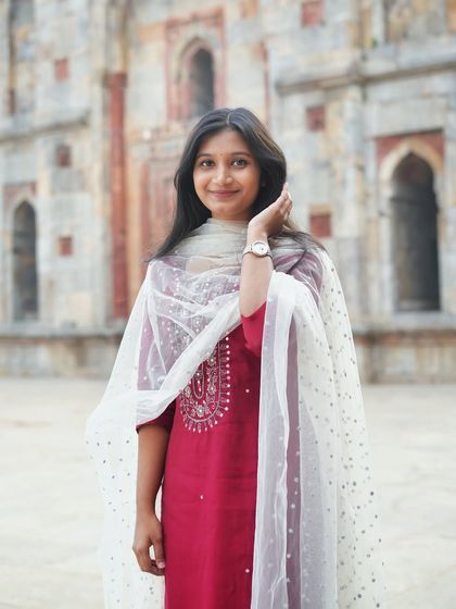 A simple and elegant portrait in a maroon suit. The soft focus on the historic background keeps the attention on her graceful pose and the beautiful ethnic wear.