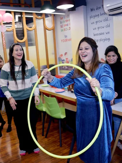 The pure joy of game time. This photo captures the laughter and excitement as a guest plays a hula hoop game during a party, surrounded by her cheering friends.