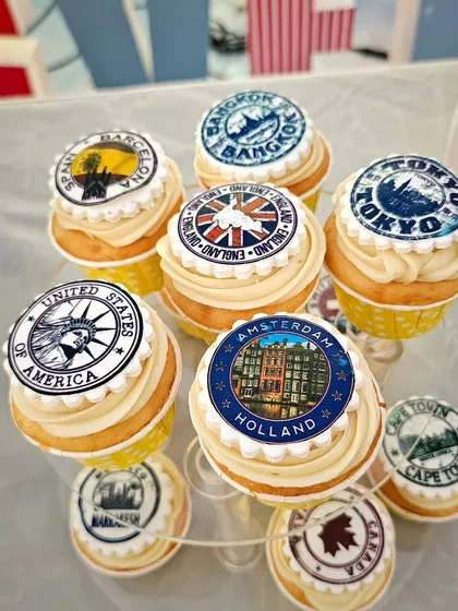 Travel-themed cupcakes with edible toppers showing passport stamps from around the world.
