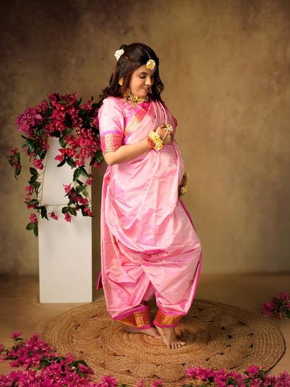 A beautiful portrait celebrating tradition. The mother-to-be is dressed in a stunning pink Nauvari saree, surrounded by flowers.