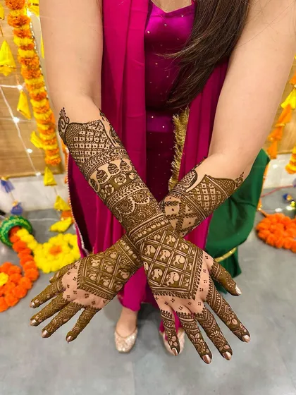 This design is a beautiful example of symmetry and detail, with repeating elephant and geometric patterns creating a tapestry of art on the forearms.