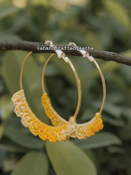 The yellow 'Naazakat' hoops captured in a natural setting. The color just pops against the green leaves, showing off their vibrant, happy vibe.
